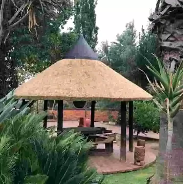A thatched gazebo framed by lush garden foliage