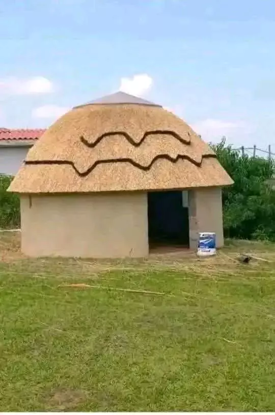 A round thatched hut in a grassy field