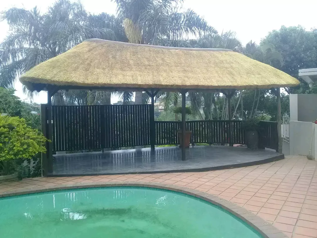 A thatched gazebo beside a swimming pool